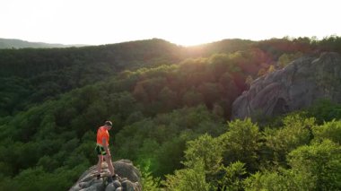 Ukrayna 'daki Karpat Dağları' ndaki Dovbush Kayalıkları 'ndaki kaya oluşumunun havada görünen görüntüsü. Güneş batıyor, yemyeşil orman, uzak tepeler üzerine ılık bir parıltı saçıyor, nefes kesici bir manzara yaratıyor..