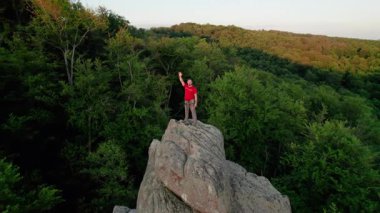 Ukrayna 'daki Karpat Dağları' ndaki Dovbush Kayalıkları 'ndaki kaya oluşumunun havada görünen görüntüsü. Güneş batıyor, yemyeşil orman, uzak tepeler üzerine ılık bir parıltı saçıyor, nefes kesici bir manzara yaratıyor..