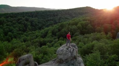 Ukrayna 'daki Karpat Dağları' ndaki Dovbush Kayalıkları 'ndaki kaya oluşumunun havada görünen görüntüsü. Güneş batıyor, yemyeşil orman, uzak tepeler üzerine ılık bir parıltı saçıyor, nefes kesici bir manzara yaratıyor..