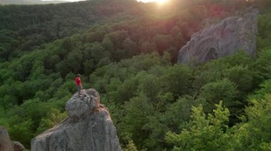 Ukrayna 'daki Karpat Dağları' ndaki Dovbush Kayalıkları 'ndaki kaya oluşumunun havada görünen görüntüsü. Güneş batıyor, yemyeşil orman, uzak tepeler üzerine ılık bir parıltı saçıyor, nefes kesici bir manzara yaratıyor..