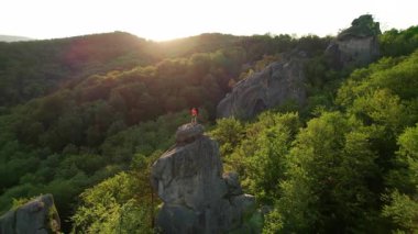 Ukrayna 'daki Karpat Dağları' ndaki Dovbush Kayalıkları 'ndaki kaya oluşumunun havada görünen görüntüsü. Güneş batıyor, yemyeşil orman, uzak tepeler üzerine ılık bir parıltı saçıyor, nefes kesici bir manzara yaratıyor..