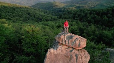 Ukrayna 'daki Karpat Dağları' ndaki Dovbush Kayalıkları 'ndaki kaya oluşumunun havada görünen görüntüsü. Güneş batıyor, yemyeşil orman, uzak tepeler üzerine ılık bir parıltı saçıyor, nefes kesici bir manzara yaratıyor..