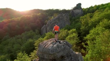 Ukrayna 'daki Karpat Dağları' ndaki Dovbush Kayalıkları 'ndaki kaya oluşumunun havada görünen görüntüsü. Güneş batıyor, yemyeşil orman, uzak tepeler üzerine ılık bir parıltı saçıyor, nefes kesici bir manzara yaratıyor..