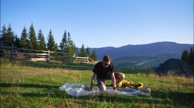 Yürüyüşçü otlak yamaçta turist çadırı kurdu. Çam ağaçları ve açık mavi gökyüzünün altındaki uzak dağlar.