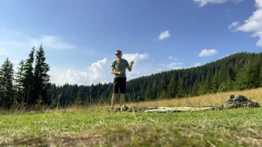Yürüyüşçü otlak yamaçta turist çadırı kurdu. Çam ağaçları ve açık mavi gökyüzünün altındaki uzak dağlar.