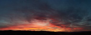 Göz kamaştırıcı günbatımı gökyüzünü kırmızı, turuncu ve pembe renkleriyle boyar. Derin maviler ve morlar ile harmanlanır. Siluetli tepeler, ateşli ufka karşı tezat oluşturarak, huzurlu manzaraya dram katıyor..