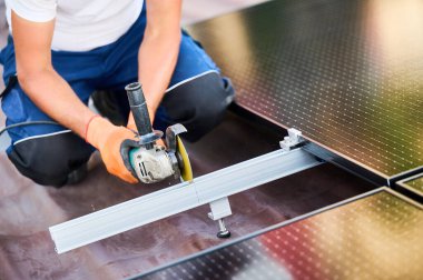 Evin çatısına fotovoltaik güneş paneli kuran ya da koruyan işçiler. Montaj yapısının metal kısmında öğütücü kullanan teknisyenleri kapatın. Kavramsal yenilenebilir enerji.