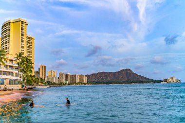 Honolulu, Waikiki, Hawaii - April 26, 2022 Colorful Waikiki Beach Surfers Swimmers Evening Diamond Head Hotels Honolulu Hawaii clipart