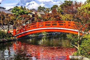 Colofrul Red Bridge Pond Reflection Shinsenen Garden Public Park Kyoto Japan.  Oldest spot in Kyoto. Garden created by Emperor Kammu in 794 as his moon viewing garden. Scholars think that the garden still exists because pond was used to put out fires clipart