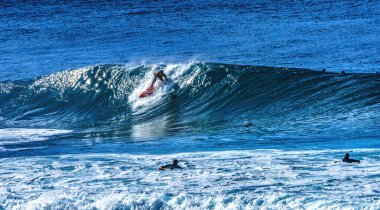 Renkli Sörfçü, Banzai Boru Hattı Dalgası üzerinden Kuzey Kıyısı Oahu Hawaii 'ye gidiyor. Sığ resifin üzerindeki dalgalar, sörfçülerin binebileceği büyük, içi boş su kıvrımları oluşturur. Sığ resif sörf yapmak için tehlikeli ve güzel bir yer yaratır..
