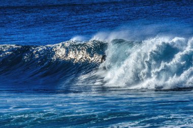 Renkli sörfçü Büyük Dalgalı Banzai Boru Hattı Kuzey Kıyısı Oahu Hawaii. Sığ resifin üzerindeki dev dalgalar, sörfçülerin binebileceği büyük, içi boş su kıvrımları oluşturur. Sığ resif sörf yapmak için tehlikeli ve güzel bir yer yaratır..