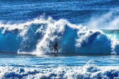 Renkli sörfçü Büyük Dalgalı Banzai Boru Hattı Kuzey Kıyısı Oahu Hawaii. Sığ resifin üzerindeki dev dalgalar, sörfçülerin binebileceği büyük, içi boş su kıvrımları oluşturur. Sığ resif sörf yapmak için tehlikeli ve güzel bir yer yaratır..