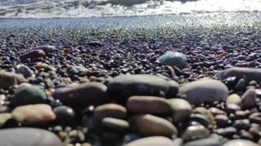 Deniz çakıl taşları ve deniz dalgaları arka planı. Yaz seyahatleri, tatil plajları ve okyanus rahatlığı. Yüksek kalite 4k görüntü