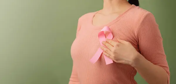 Breast Cancer Awareness Campaign Concept. Women Healthcare. Close up of a Young Female Touching Pink Ribbon on her Thorax