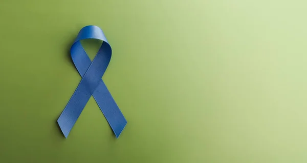Prostate Cancer Awareness Campaign Concept. Men Healthcare. Close up of a Blue Ribbon Lying on Green background, Top View