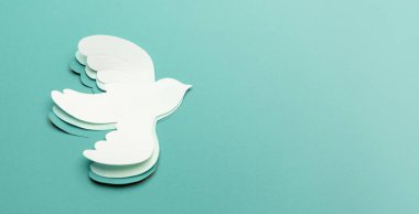 Barış ve Umut 'un Yeni Başlangıçları. Mavi arka planda uçan beyaz bir güvercin. Dünya Uluslararası Barış Günü. Dünyaya kağıttan yapılmış barışçıl bir kuş konsepti.