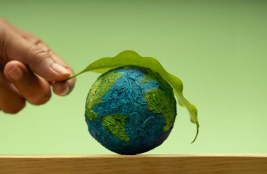 Dünya 'ya yeşil yaprak koyuyor. Çevresel sürdürülebilirlik, Dünya Günü, küresel ekolojik bakım ve sağlıklı gezegen Globe