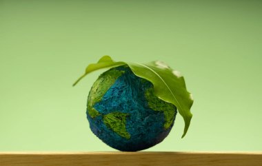 Yeşil yaprak yeşil arka planda minyatür Dünya 'yı dinlendiriyor. Çevresel sürdürülebilirlik, Dünya Günü, küresel ekolojik bakım ve sağlıklı gezegen Globe