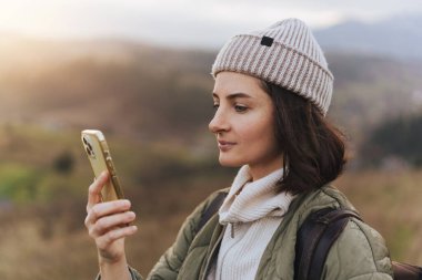 Ormanda yürürken cep telefonunda internet haritası kullanan kadın yolcuların ekili fotoğrafı, modern cep telefonu cihazını tutan kadın elleri.