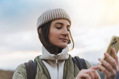 Kadın elinin cep telefonu tutarken ve internette gezinirken çekilmiş görüntüsü. Yürüyüş yaparken ve ormanda kablosuz bağlantı kullanılarak.