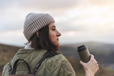 Dişi dağcı elinde su şişesiyle güzel manzaraya bakıyor. Uçurumda duran ve su içen bir kadın yürüyüşçü.. 