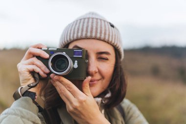 Gülümseyen kadın fotoğrafçının portresi. Eski fotoğraf makinesiyle dağların fotoğraflarını çekiyor. Kırsal kesimde ormanın etrafında dolaşırken.