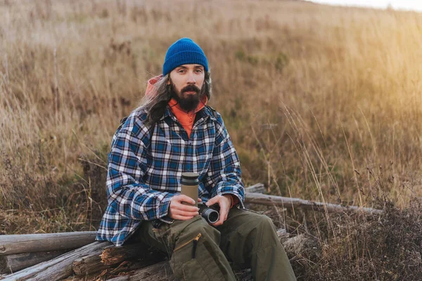 日没と山の水とヴィンテージ写真カメラのボトルと写真家の男の肖像画 旅行のバックパックと山の中でハイカー若い男性ハイキングの水平方向の肖像画 健康的なライフスタイルの概念 — ストック写真