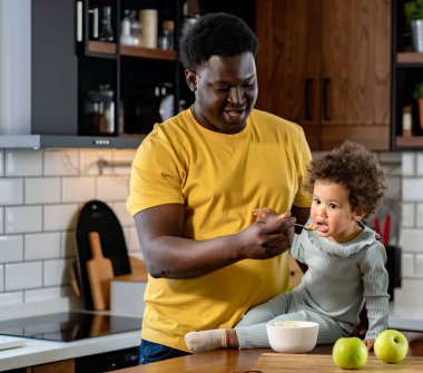 father feeding his daughter on kitchen