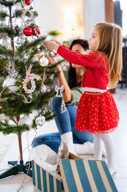 Güzel anne ve kız Noel ağacı süslüyorlar.