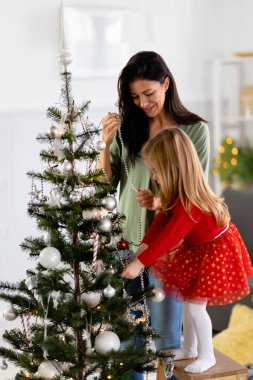Güzel anne ve kız Noel ağacı süslüyorlar.