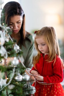 Güzel anne ve kız Noel ağacı süslüyorlar.