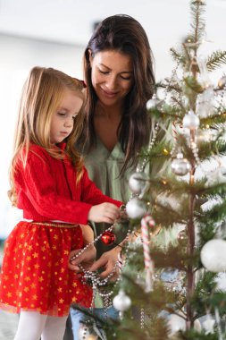 Güzel anne ve kız Noel ağacı süslüyorlar.