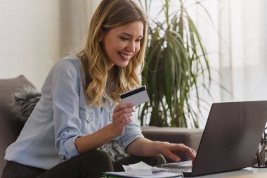 Ofisinde dizüstü bilgisayarı ve kredi kartı olan genç ve güzel bir kadın online sipariş veriyor.