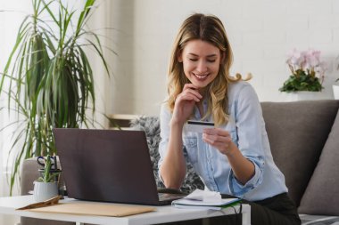 Ofisinde dizüstü bilgisayarı ve kredi kartı olan genç ve güzel bir kadın online sipariş veriyor.