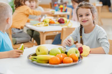 Çocuklar öğle arasında anaokulunda meyve yiyorlar.
