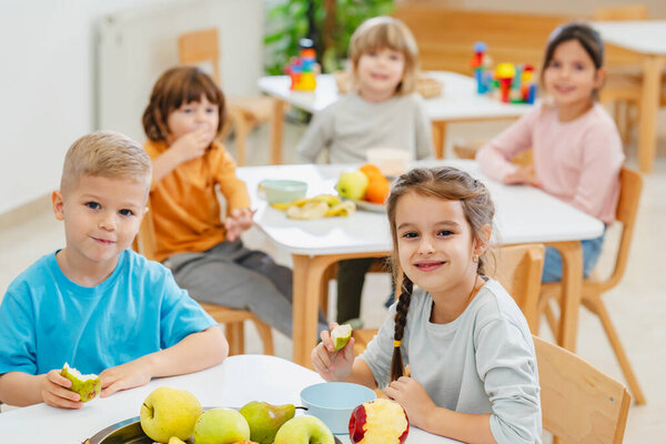 children eating fruits at lunch break in kindergarten