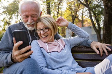 Park yerinde telefon kullanan yaşlı çift. 