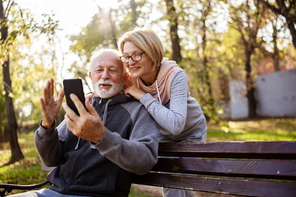 senior couple using phone in park