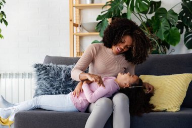 Afro-Amerikan anne ve kızı evde birlikte vakit geçiriyorlar.