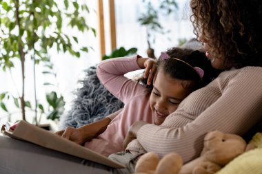 Afrikalı Amerikalı kız ve anne kitap okuyor.