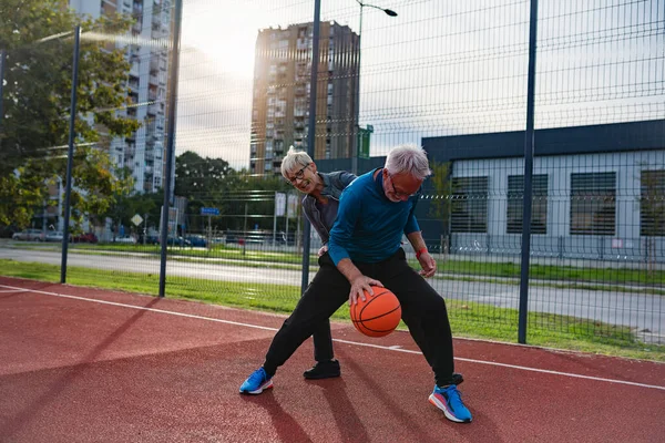 stock image senior couple playing basketball outdoors