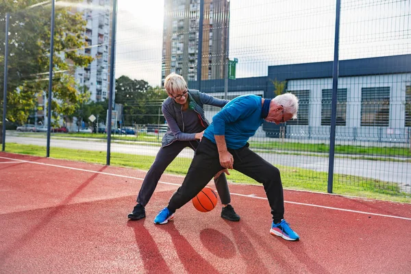 stock image senior couple playing basketball outdoors