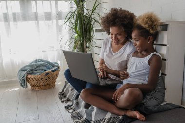 Afro-Amerikan anne ve kızı dizüstü bilgisayar kullanıyor.