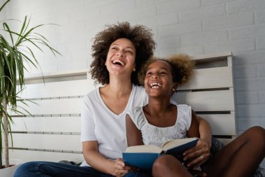 Afrika kökenli Amerikalı anne ve kız kitap okuyor.