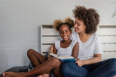 Afrika kökenli Amerikalı anne ve kız kitap okuyor.
