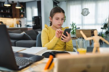 Okul çocuğu cep telefonuyla çok fazla zaman harcıyor. Genç liseli kız evde akıllı telefon izliyor..