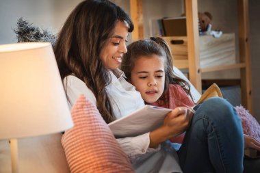 Anne ve kızı kitap okuyor. 