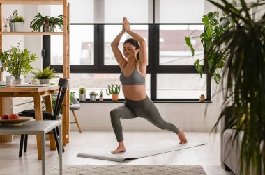 Genç ve güzel bir kadın evde pilates yapıyor. Fitness, yaşam tarzı, spor, sağlıklı insanlar.