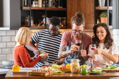 Genç insanlar evde tatil partisi veriyor, yemek hazırlıyor, içiyor, konuşuyor ve eğleniyorlar.