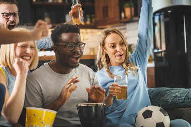 Heyecanlı, çok ırklı bir grup genç, evlerinde TV 'de futbol maçı izliyor.